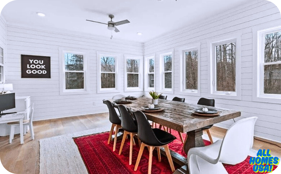 Bright dining room with a rustic table, black chairs, a large window, a motivational wall art, and a computer desk. Cozy and inviting atmosphere. Image for illustrative purpose.