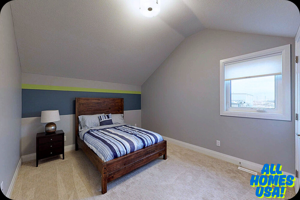 Cozy bedroom with a sloped ceiling, wooden bed featuring striped blue bedding, and a nightstand with a lamp. A window offers natural light. Image for illustrative purpose.