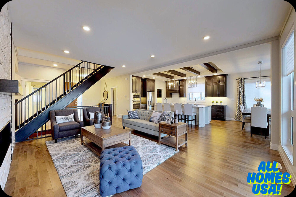 Stylish open-concept living room with modern furniture, wood flooring, and a staircase. Adjoining kitchen features dark cabinets and a dining area. Cozy and inviting ambiance. Image for illustrative purpose.