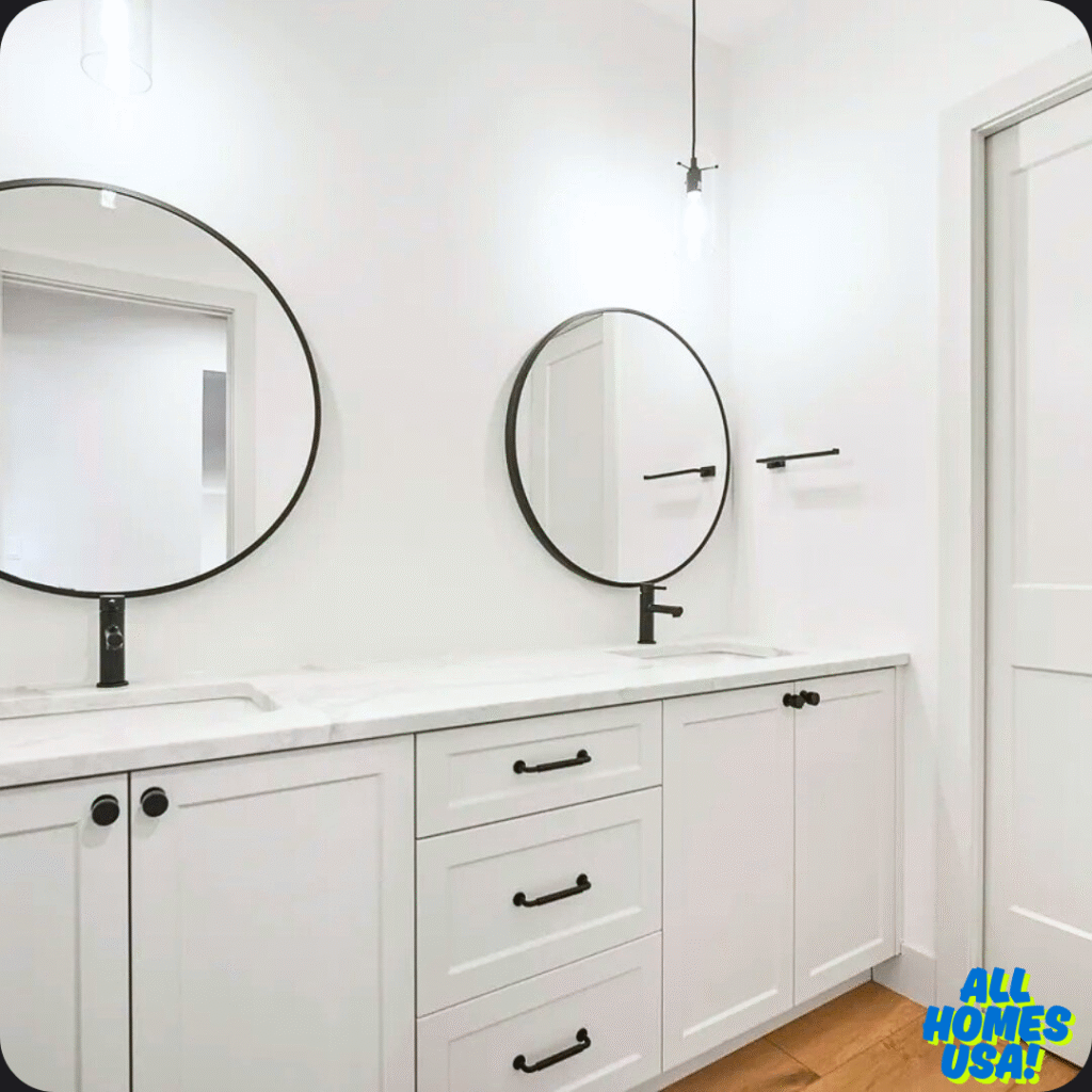Modern bathroom with two round mirrors above a white double-sink vanity. Black fixtures contrast with white walls and wooden floor, creating a sleek, minimalist look. Image for illustrative purpose.