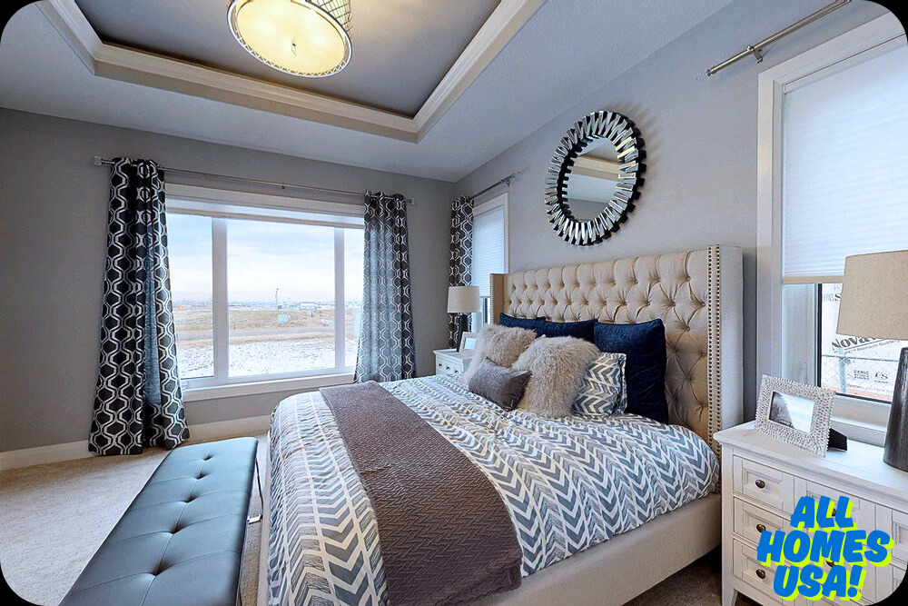 Elegant bedroom with a gray and white color scheme. Features a tufted headboard, chevron bedding, plush pillows, a round mirror, and large windows with geometric curtains. Image for illustrative purpose.