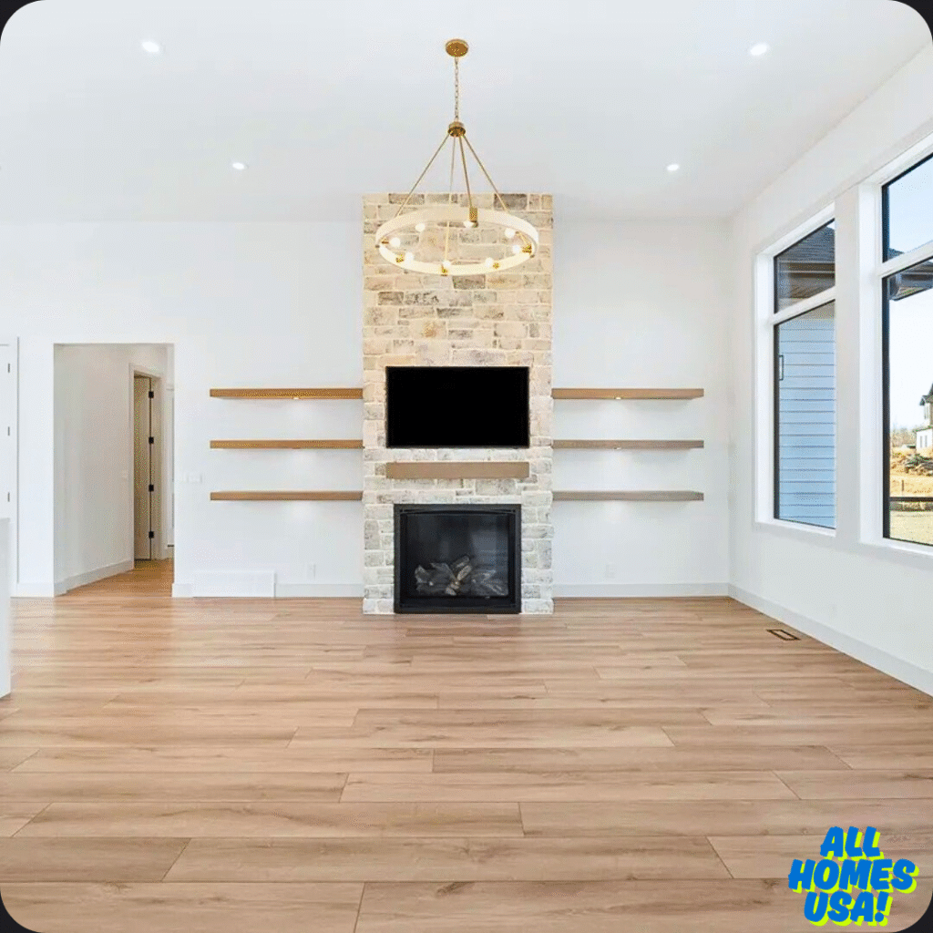 Modern living room with light wood floors, a stone fireplace, and a mounted TV. Open shelves flank the fireplace. Large windows enhance brightness. Elegant chandelier centered. Image for illustrative purpose.