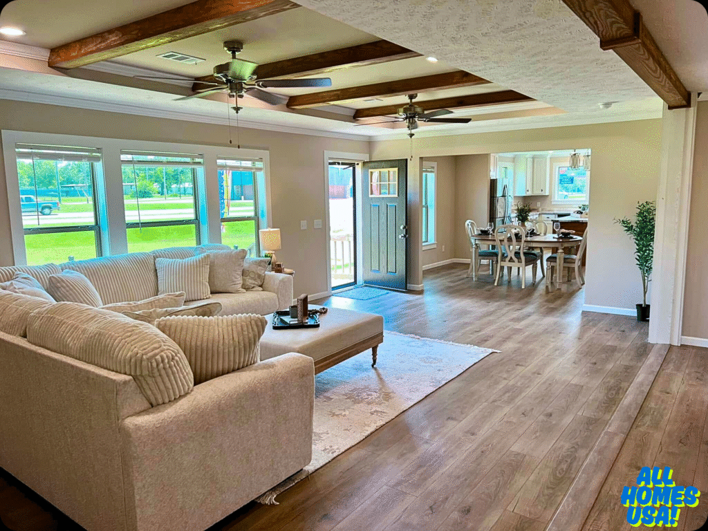 Spacious living room with beige sectional sofa, large windows, and wooden beams. Dining area and kitchen in the background. Bright, airy ambiance. Image for illustrative purposes.