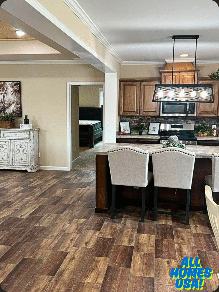 Warm, inviting kitchen with wooden cabinets, a modern hanging light fixture, and beige accents. Rustic wood flooring extends to the cozy dining area. Image for illustrative purpose.
