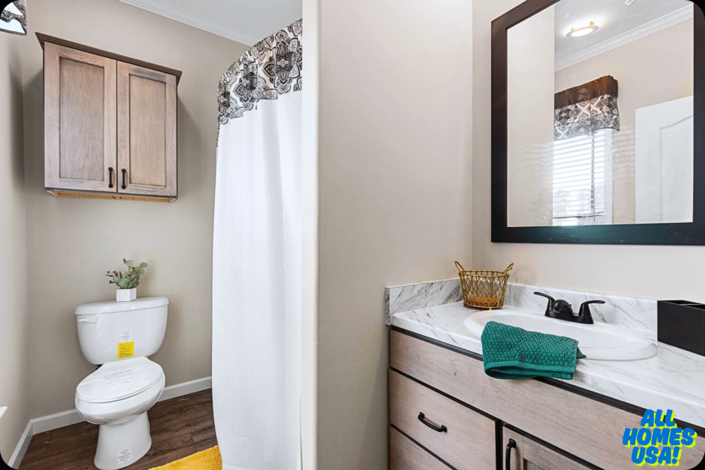 A modern bathroom features beige walls, a wooden cabinet, a white toilet with a plant, a shower with a white curtain, and a vanity with a mirror. Image for illustrative purpose.