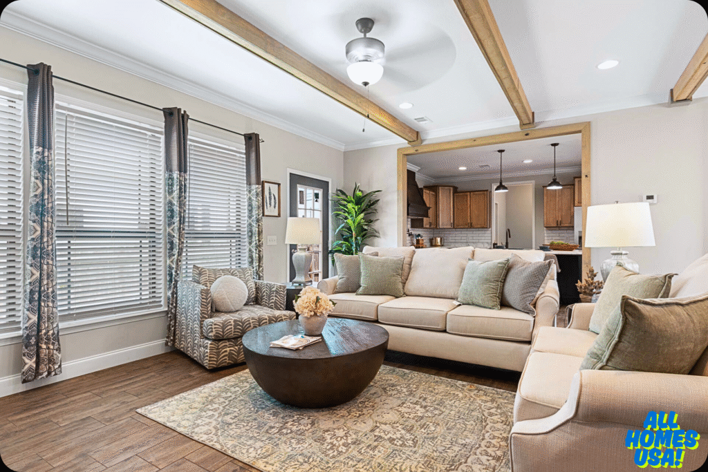 Cozy living room with beige sofas, a patterned armchair, and a round coffee table. Wooden beams and large windows create a warm, inviting ambiance. Image for illustrative purpose.