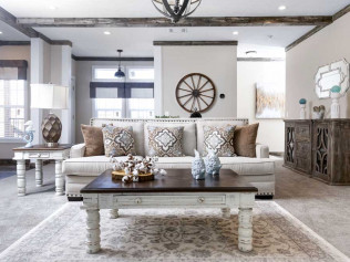 Modern living room with neutral tones features a plush sofa with decorative pillows, a rustic wooden coffee table, and stylish decor, creating a cozy, elegant atmosphere.