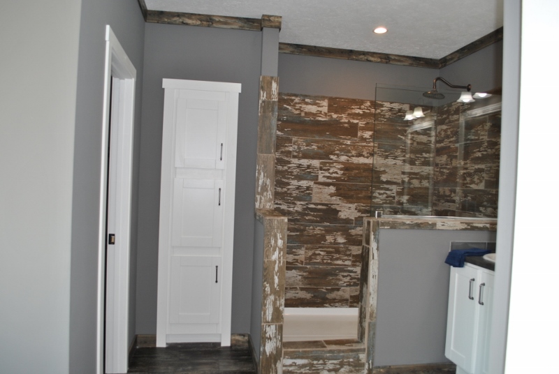 Modern bathroom with rustic wood-tiled shower, white cabinetry, and gray walls. The decor is contemporary, evoking a calm, stylish ambiance.