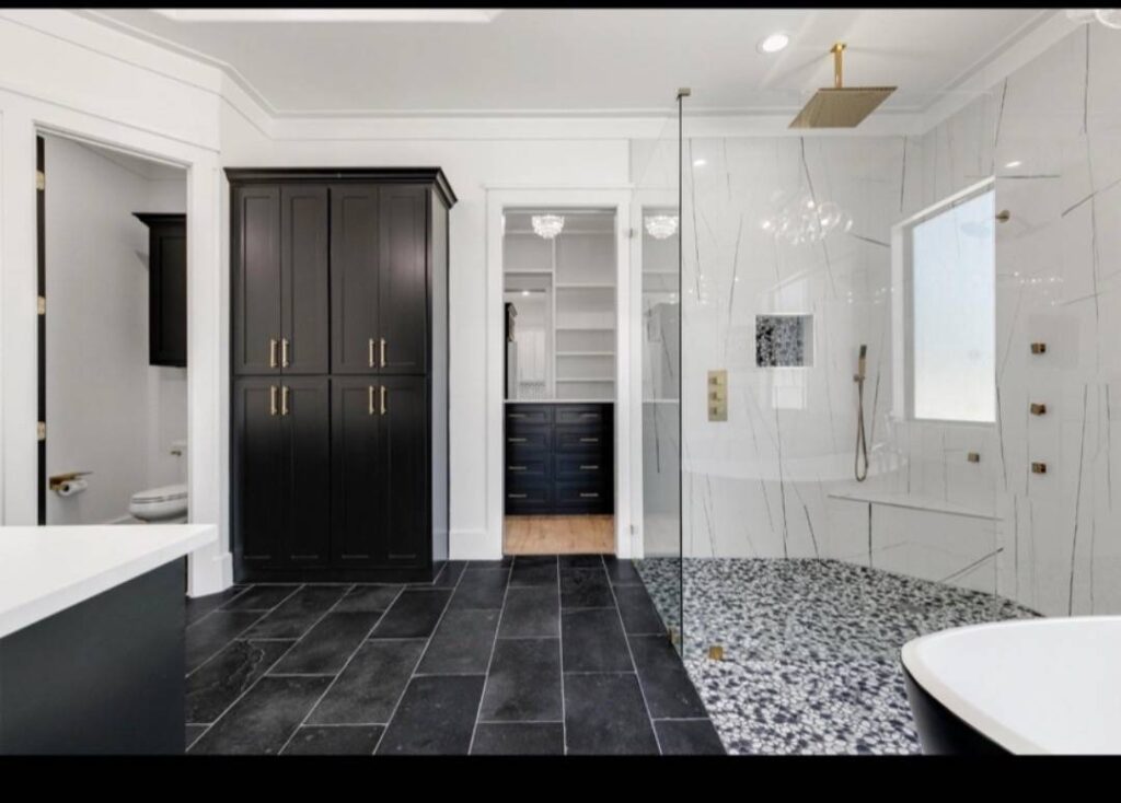Modern bathroom with black cabinets, glass shower, and sleek fixtures. Black and white tiles create a sophisticated contrast. Bright and elegant design. Image for illustrative purposes.