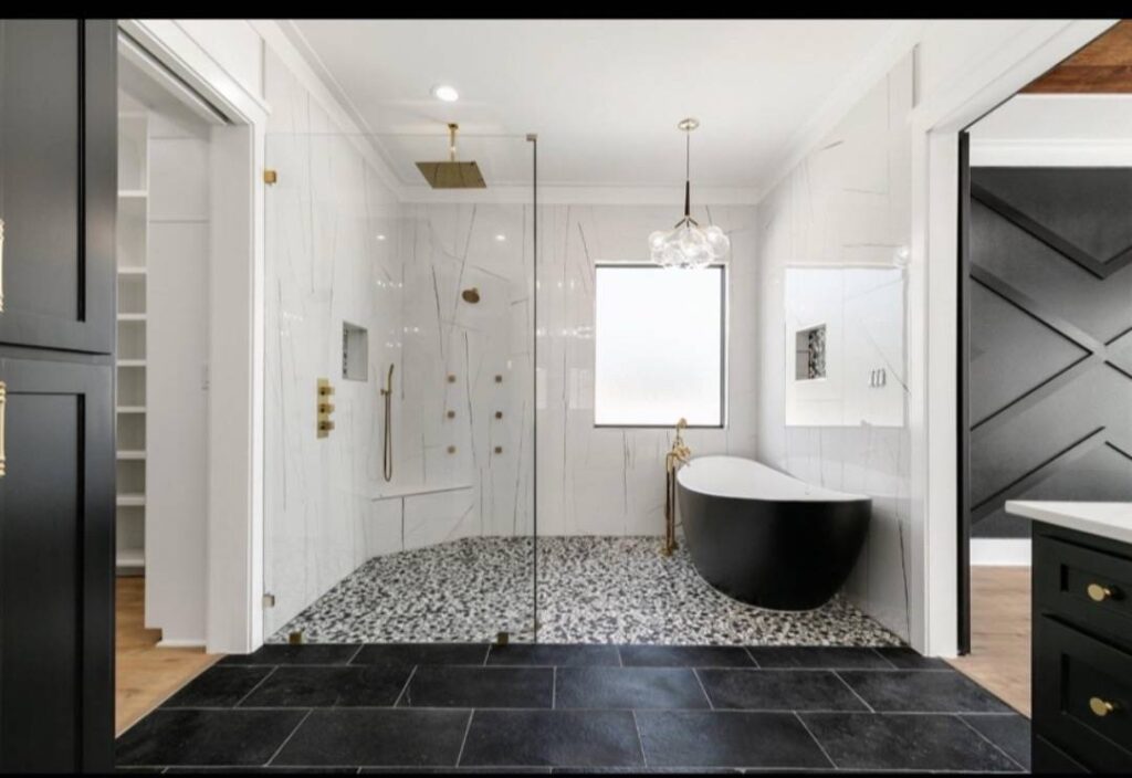 Luxurious bathroom with a glass shower, black freestanding bathtub, elegant marble walls, and black tiled floor, creating a modern, serene feel. Image for illustrative purposes.