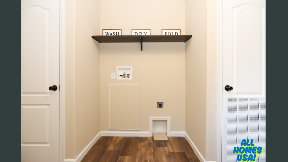 Laundry room with wood floor, shelf with "WASH," "DRY," "FOLD" signs. Beige walls, minimal decor, utility connections visible, inviting neat space. Image for illustrative purposes.