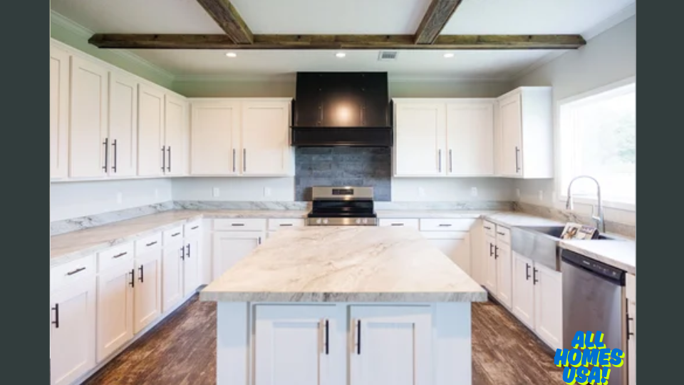 Spacious kitchen with white cabinets, dark appliances, and a marble island. Wooden ceiling beams add rustic charm. Sunlight streams through a large window. Image for illustrative purposes.
