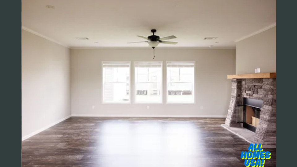 Spacious empty room with wooden floor, ceiling fan, large windows, and a stone fireplace. Bright and airy, conveying a modern, cozy atmosphere. Image for illustrative purposes.