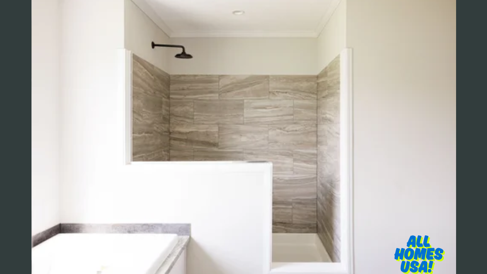 Modern bathroom with stone-tiled shower, white walls, and sleek fixtures. A sense of cleanliness and simplicity. Logo in the corner: "All Homes USA!". Image for illustrative purposes.